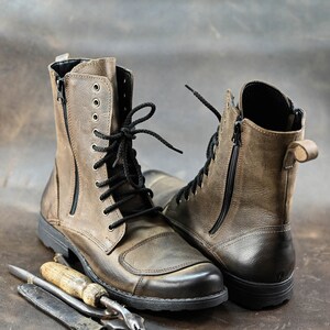 May include: A pair of brown leather boots with black laces and zippers. The boots have a rugged look and are made of distressed leather.