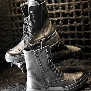 Puede incluir: Dos pares de botas de cuero negro con cordones y cremalleras. Las botas tienen una suela gruesa y est&aacute;n hechas de cuero desgastado.