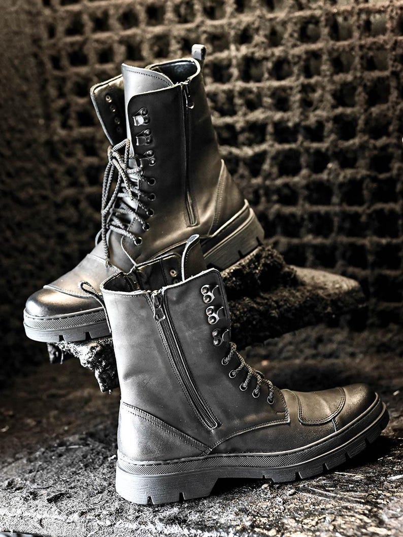 Puede incluir: Dos pares de botas de cuero negro con cordones y cremalleras. Las botas tienen una suela gruesa y est&aacute;n hechas de cuero desgastado.