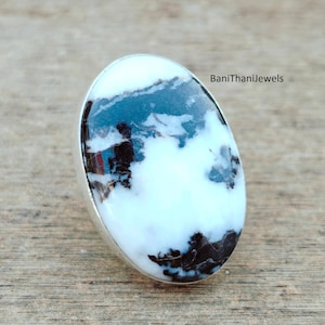 May include: Oval ring with a white stone, patterned with black and grey, set in a silver band. The stone's design resembles clouds. The text "BaniThanijewels" is visible on the right. This ring is a piece of jewellery.