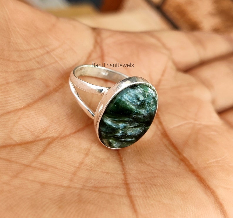 May include: A silver ring with a green and gray gemstone. The ring has a simple band with a split design.