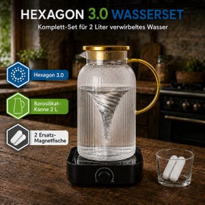 May include: A clear, ribbed glass pitcher with a gold lid and handle, sitting on a black magnetic base that creates a water vortex. The set includes two white magnetic stir bars in a small glass. Text reads HEXAGON 3.0 WASSERSET.