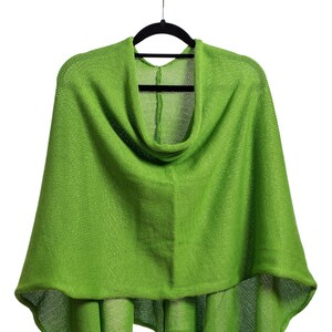 May include: A green knitted poncho with a cowl neck and a loose fit.