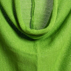 May include: Close-up of a green knitted fabric with a cowl neck. The fabric is soft and has a subtle sheen.