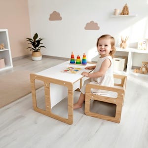 Puede incluir: Un conjunto de mesa y silla infantil de madera clara con tablero y asiento blancos. La mesa presenta una superficie rectangular blanca sostenida por patas de madera clara, y la silla a juego tiene un diseño de marco de madera simple.