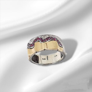 Könnte beinhalten: Ein Silber- und Goldring mit einer Reihe roter Edelsteine. Der Ring ist mit "925" und "585" gekennzeichnet.