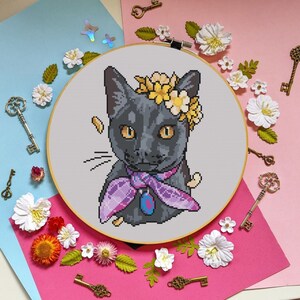 Peut inclure: Un chat noir avec des fleurs jaunes dans les cheveux et une écharpe violette autour du cou. Le chat regarde directement le spectateur. L'image est un motif de point de croix.