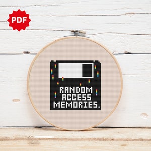Peut inclure: Un motif de point de croix représentant un disque souple noir avec le texte "RANDOM ACCESS MEMORIES." Le disque souple est entouré de pixels colorés.