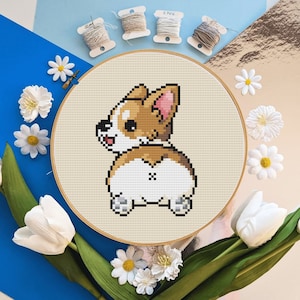 Peut inclure: Un motif de point de croix représentant un chien corgi brun et blanc, vu de dos. Le chien est assis sur un fond beige.