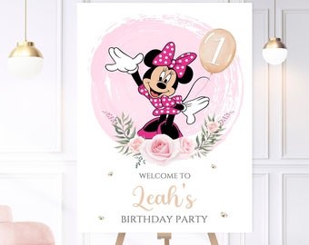 Può includere: Un cartello di benvenuto rosa e bianco con un'immagine di Minnie Mouse dei cartoni animati che tiene un palloncino con su scritto "1". Il cartello dice "Benvenuti alla festa di compleanno di Leah".