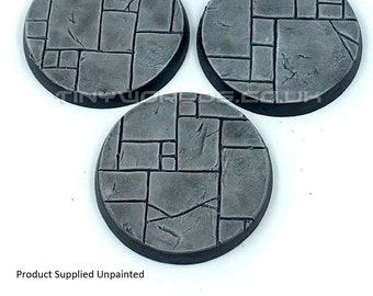 May include: Three gray, circular bases with a stone-like texture. Each base is divided into irregular rectangular shapes, with a dark border. The text "Product Supplied Unpainted" is visible at the bottom.