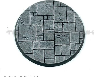 May include: A circular, unpainted base with a textured stone pattern. The base is dark gray with a black rim. The surface is divided into irregular, rectangular shapes. The text "Product Supplied Unpainted" is at the bottom.