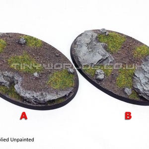 Könnte beinhalten: Zwei ovale Miniaturbasen mit strukturierter Oberfläche, die Felsformationen und grüne Vegetation aufweisen. Die Basen sind unbemalt und bereit zur individuellen Gestaltung. Die Buchstaben "A" und "B" sind sichtbar.