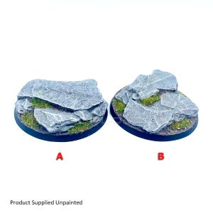 May include: Two circular miniature bases labelled A and B, featuring textured grey rock formations with patches of green static grass. The rocks have jagged edges and realistic stone detailing. The text Product Supplied Unpainted is visible.