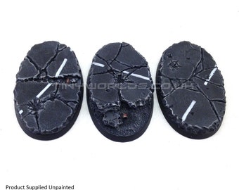 May include: Three oval-shaped miniature bases with a cracked asphalt design. The bases are dark gray with white lines and a black border. The text "Product Supplied Unpainted" is at the bottom.