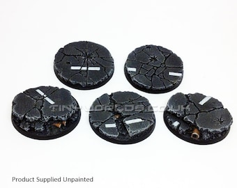 May include: Five unpainted, round miniature bases with a cracked asphalt design. Each base features a white road marking and a dark gray color scheme, with a black base rim. The text "Product Supplied Unpainted" is at the bottom.