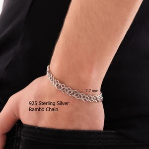 May include: A 925 sterling silver Rambo chain bracelet with an intricate interlocking link design. The metal has a polished finish and the chain width is clearly labeled as 7.7 mm on the image. The bracelet is worn around the wrist.