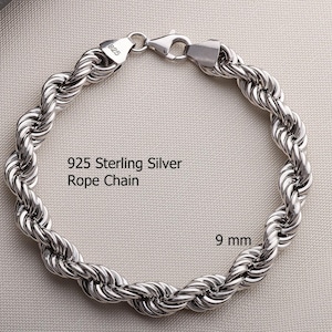 Pode incluir: Uma pulseira de corrente de corda em prata esterlina 925 de 9 mm com um fecho lagosta. O metal tem um acabamento polido e reflexivo. O texto 925 Sterling Silver Rope Chain e 9 mm est&aacute; impresso na imagem, indicando o material e a largura.