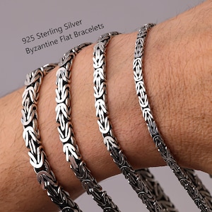 Könnte beinhalten: Vier flache byzantinische Armbänder aus 925er Sterlingsilber mit einem komplexen ineinandergreifenden Gliedermuster. Der Text 925 Sterling Silver Byzantine Flat Bracelets ist in der oberen linken Ecke sichtbar. Die Silberketten haben ein poliertes Finish mit dunklen oxidierten Akzenten zwischen den Gliedern, was ein ausgeprägtes strukturiertes Erscheinungsbild auf der Metalloberfläche erzeugt.