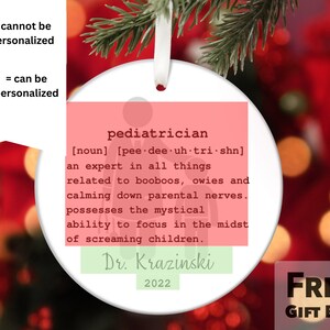 May include: A white round Christmas ornament with a pink and green design. The ornament features a definition of the word "pediatrician" with the text "Dr. Krazinski 2022".