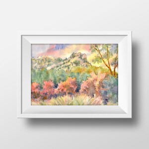 May include: Watercolor painting of a mountain landscape with a sunset sky. The mountains are green and brown, and the sky is a mix of pink, orange, and yellow. There are trees in the foreground, and the painting has a soft, dreamy feel.