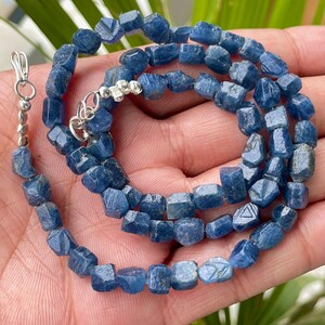 Può includere: Una collana realizzata con perline di zaffiro blu sfaccettate. Le perline sono di un blu intenso e hanno una forma leggermente irregolare. La collana è infilata su una catena d'argento.