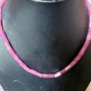 May include: A pink gemstone necklace with rectangular beads. The necklace is made of pink gemstones and silver.