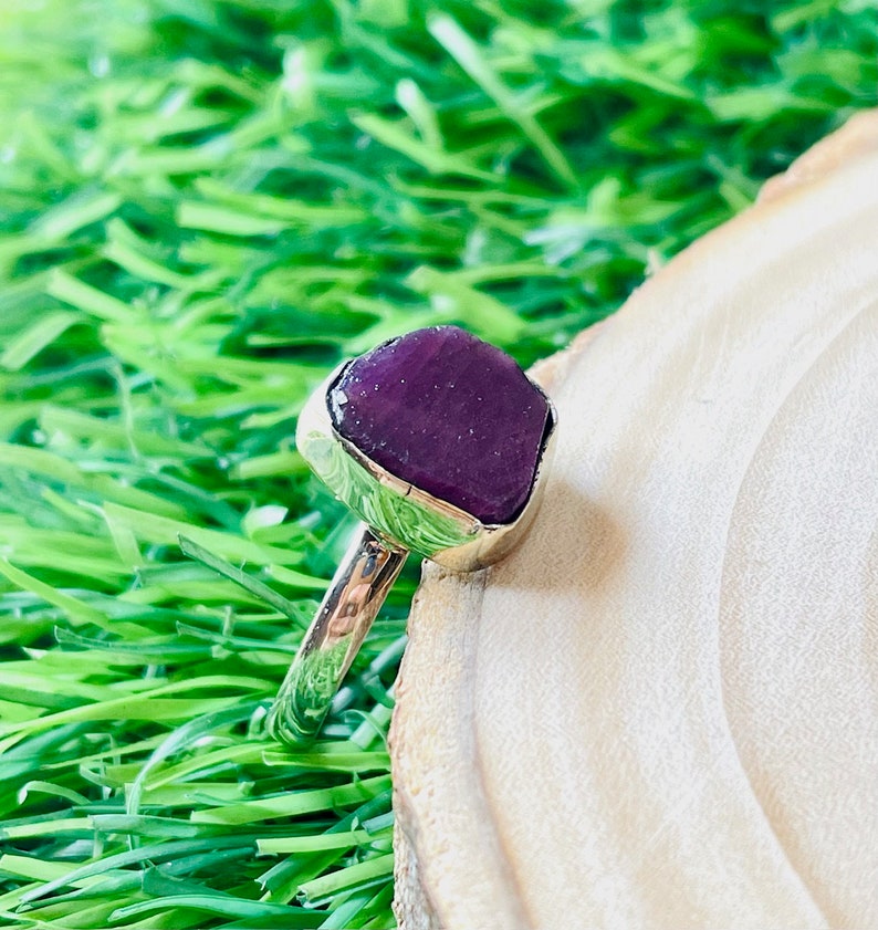 May include: A silver ring with a large, faceted, purple gemstone set in a bezel setting.