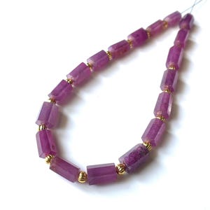 May include: A strand of purple gemstone beads with gold accents. The beads are rectangular in shape and have a slightly irregular, natural look.