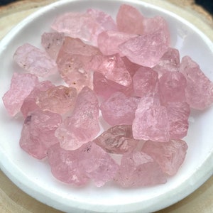 Puede incluir: Una colecci&oacute;n de cristales de cuarzo rosa de diferentes formas y tama&ntilde;os. Los cristales est&aacute;n pulidos y tienen un acabado liso y brillante.