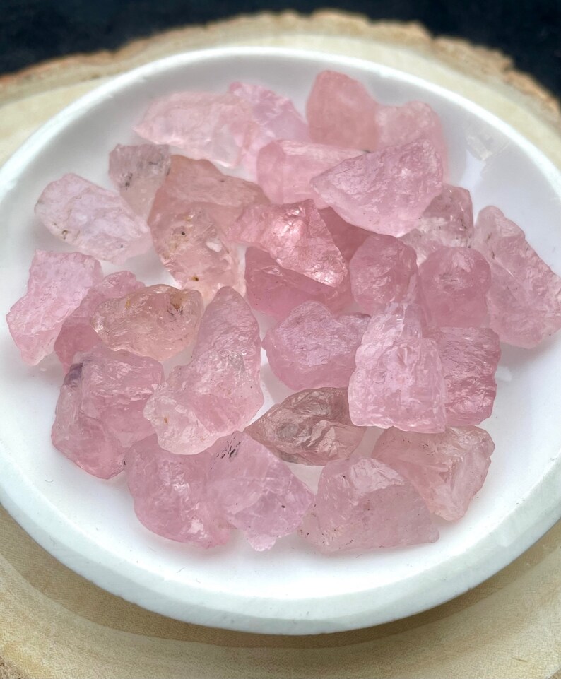 Puede incluir: Una colecci&oacute;n de cristales de cuarzo rosa de diferentes formas y tama&ntilde;os. Los cristales est&aacute;n pulidos y tienen un acabado liso y brillante.