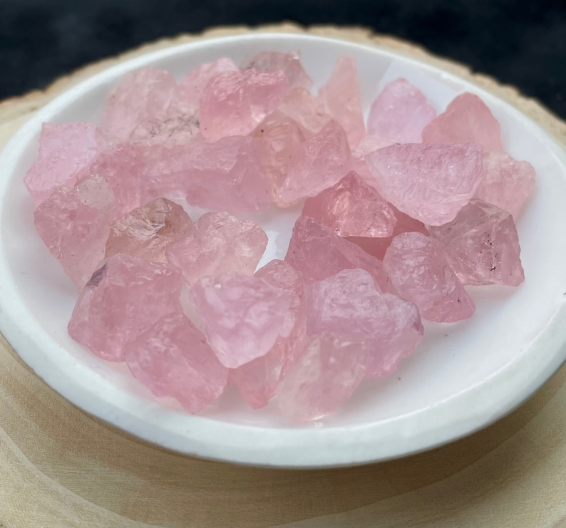 Puede incluir: Una colecci&oacute;n de cristales de cuarzo rosa de diferentes tama&ntilde;os y formas. Los cristales est&aacute;n pulidos y tienen un acabado liso y brillante.