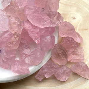 Puede incluir: Un mont&oacute;n de cristales de cuarzo rosa sobre un plato blanco. Los cristales son &aacute;speros y tienen un aspecto natural y sin pulir.