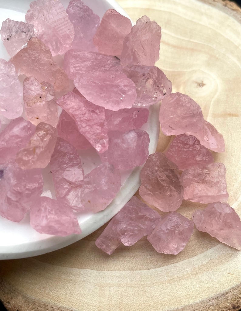 Puede incluir: Un mont&oacute;n de cristales de cuarzo rosa sobre un plato blanco. Los cristales son &aacute;speros y tienen un aspecto natural y sin pulir.