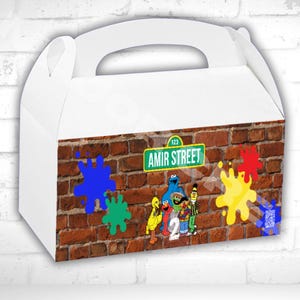 May include: White gable box with a handle, featuring a brick wall design. The box includes colorful paint splatters and a street sign that reads "Amir Street". Sesame Street characters are also visible. The text "GABLE BOX LABEL TEMPLATE" is at the bottom.