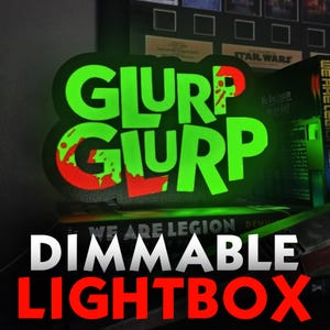 May include: A custom-shaped LED lightbox featuring the text GLURP GLURP in a bold, stylized font. The letters are illuminated in a vibrant neon green, accented with bright red, dripping-style graphic details on a black background.