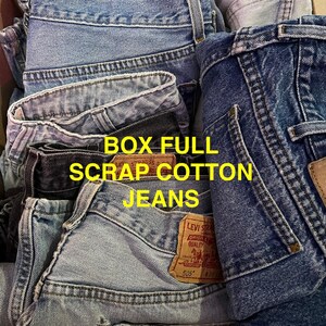 May include: A box filled with various denim jeans. The jeans are in shades of blue and gray, with visible pockets, stitching, and labels. The text "BOX FULL SCRAP COTTON JEANS" is displayed in yellow.