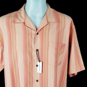 May include: A pink and white striped short-sleeved button-down shirt with a Tommy Bahama label.