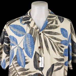 May include: A short-sleeved button-down shirt with a tropical leaf print in shades of blue, black, and beige. The shirt has a white background and a Tommy Bahama label.