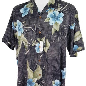 K&ouml;nnte beinhalten: Ein kurz&auml;rmeliges Hemd mit Kn&ouml;pfen, einem schwarz-wei&szlig;en Karomuster und einem blauen und gr&uuml;nen Blumendruck. Das Hemd hat einen Kragen und eine Knopfleiste.