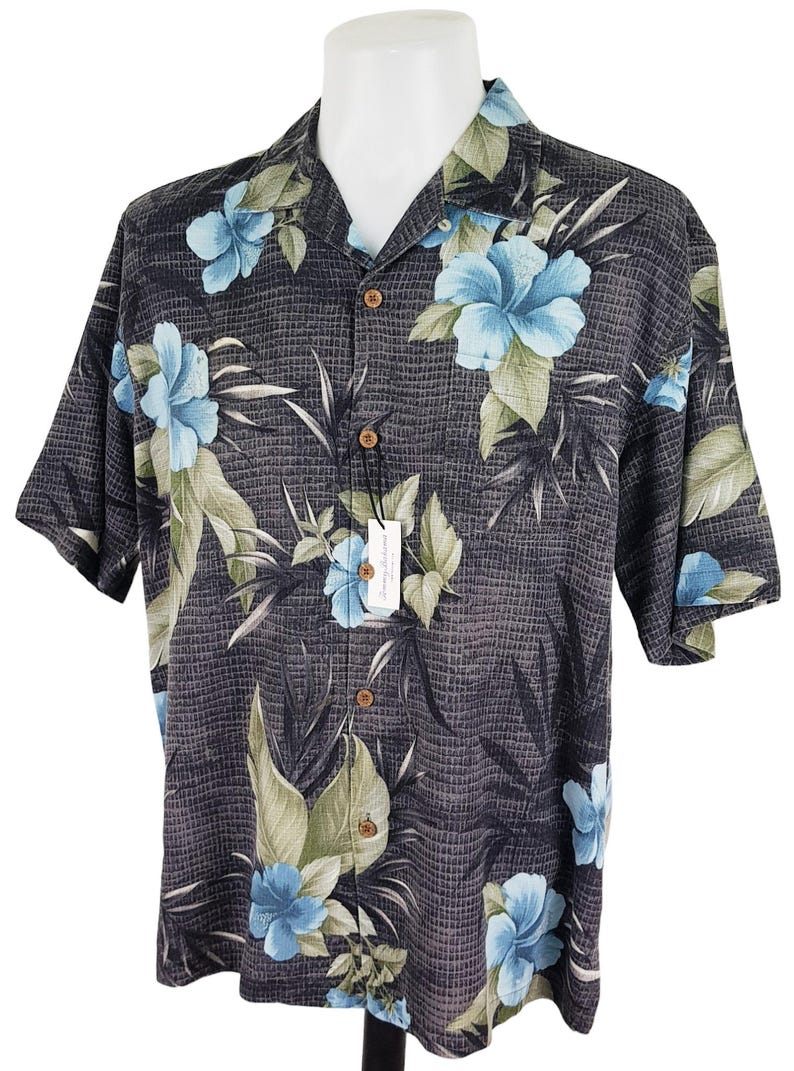 K&ouml;nnte beinhalten: Ein kurz&auml;rmeliges Hemd mit Kn&ouml;pfen, einem schwarz-wei&szlig;en Karomuster und einem blauen und gr&uuml;nen Blumendruck. Das Hemd hat einen Kragen und eine Knopfleiste.