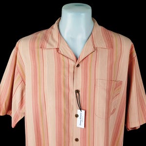 May include: A pink and green striped short-sleeved button-down shirt with a Tommy Bahama label.