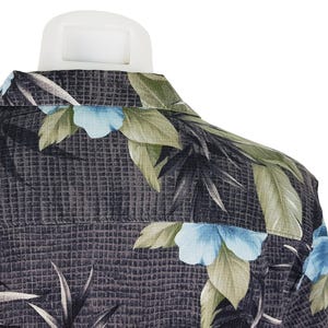 K&ouml;nnte beinhalten: Ein dunkelgraues Hemd mit Kn&ouml;pfen und einem tropischen Muster mit gr&uuml;nen Bl&auml;ttern und blauen Bl&uuml;ten.