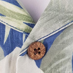 Puede incluir: Primer plano de un bot&oacute;n de coco marr&oacute;n sobre una tela estampada en blanco y azul. La tela tiene un aspecto texturizado y tejido.