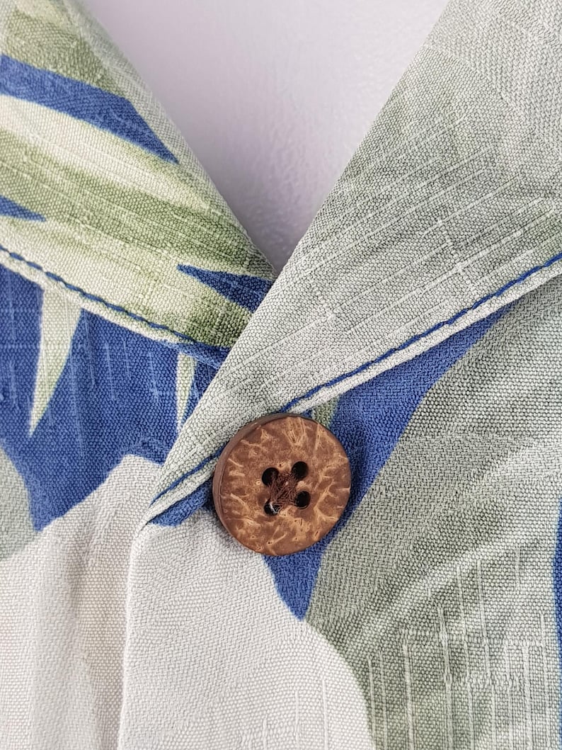 Puede incluir: Primer plano de un bot&oacute;n de coco marr&oacute;n sobre una tela estampada en blanco y azul. La tela tiene un aspecto texturizado y tejido.