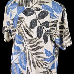 May include: A short-sleeved button-down shirt with a tropical leaf print. The shirt is white with blue and brown leaves.
