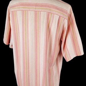 May include: A pink and beige striped short-sleeved button-down shirt.