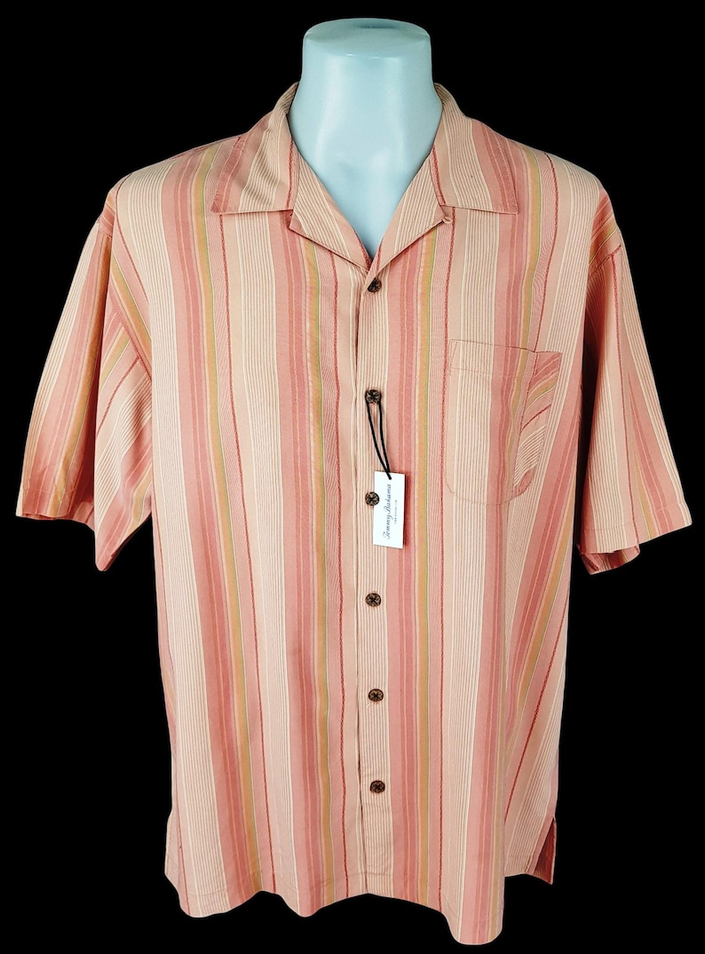 May include: A pink and white striped short-sleeved button-down shirt with a Tommy Bahama label.