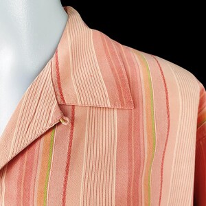 May include: A pink and green striped button-down shirt with a collar.