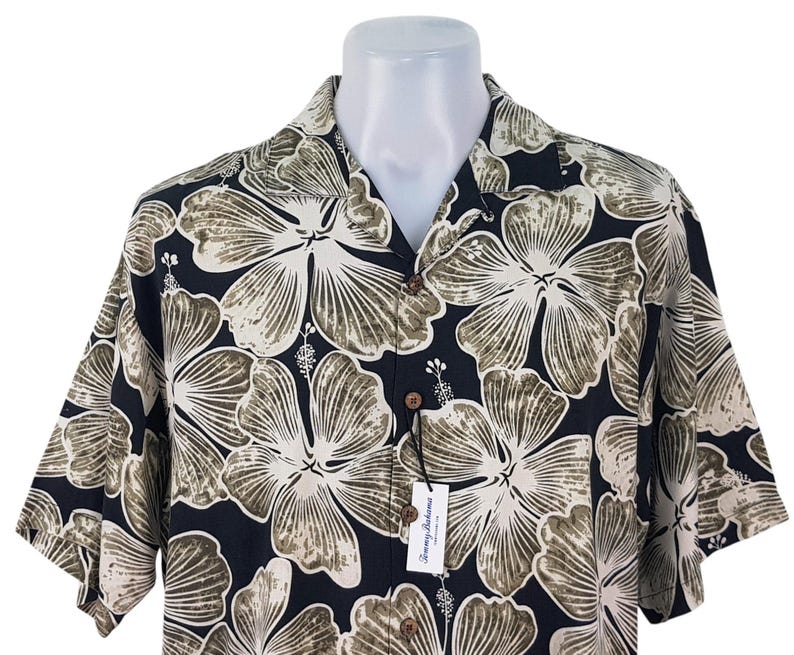 Peut inclure: Une chemise &agrave; manches courtes avec un motif floral de grande taille en beige et vert olive sur fond bleu marine. La chemise est pr&eacute;sent&eacute;e sur un mannequin blanc. Une &eacute;tiquette avec le nom de la marque est attach&eacute;e.